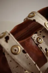 Cartera grande de cuero color marrón con asas de cuero con estampado animal print y ojales dorados.