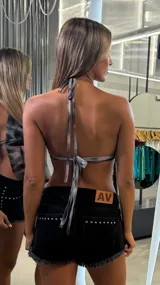 Top halter de tela liviana con estampado tie-dye en tonos grises, negros y rosados. Presenta un escote pronunciado con un aro metálico central y frunces que generan caída en la parte inferior.