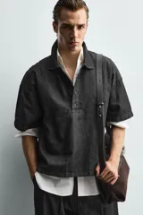 Camisa de manga corta con cuello solapa y cierre frontal de botones. Confeccionada en tejido denim de algodón, de corte relajado y aberturas laterales en el bajo.