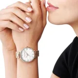 Reloj Michael Kors modelo Pyper, con caja y pulsera de acero inoxidable color oro rosa, esfera blanca con patrón de logos MK en relieve y borde con incrustaciones de strass. Resistente al agua hasta 50 metros.