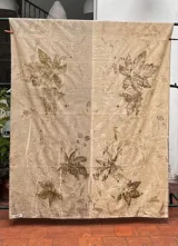 Mantel rectangular de lino y algodón en dos tonos, con estampado artesanal de hojas y flores.