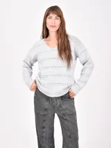 Buzo de tejido de punto color marrón oscuro, con cuello en V y detalles calados horizontales a lo largo del cuerpo y mangas.