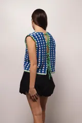 Chaleco tejido a crochet con hilado 100% algodón, con diseño a cuadros en azul y blanco, y terminaciones en verde.