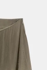 Falda midi de tiro medio confeccionada en tejido fluido con acabado satinado. Presenta diseño con godets que aportan volumen y movimiento, y bajo con detalle de encaje a tono. Cierre lateral con cremallera oculta.
