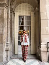 Pantalón de corte recto con estampado de cuadros en tonos rojos, marrones y beige. Presenta un diseño de tiro medio y pernera amplia.