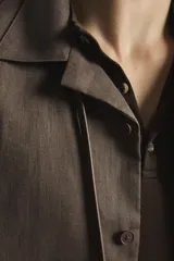 Camisa de lino color blanco, con ajuste relajado, cuello bowling, manga corta y cierre frontal con botones.