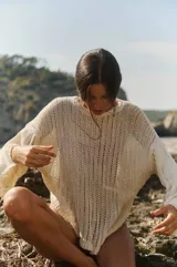 Sweater tejido color crudo, de manga larga y escote redondo. Tejido calado con caída relajada.