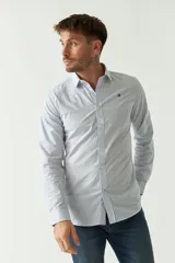 Camisa de hombre de corte slim fit, confeccionada en algodón con diseño de rayas verticales finas en tonos claros. Presenta cuello clásico, cierre frontal con botones y logo bordado en el pecho.
