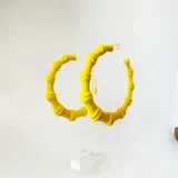 Par de argollas grandes color amarillo, con diseño tipo bambú.