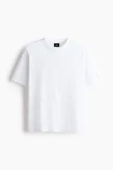 Remera de punto de algodón de peso medio, color blanco, con cuello redondo ribeteado, hombros caídos, bajo recto y corte relajado.
