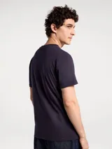 Camiseta blanca de algodón con cuello redondo y mangas cortas. Estampa rectangular con borde negro que contiene la frase "NATURAL ATMOSPHERE" en letras mayúsculas y una imagen de montañas y mar.