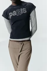 Pantalón capri de tiro medio con estampado de raya diplomática, cierre frontal con cremallera y botón metálico, y refuerzos en la zona de las rodillas.