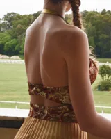 Vestido con falda plisada color dorado y top diseñado en jacquard con estampado paisley en tonos borgoña, ocre y dorado. Se ajusta al cuello con tiras de cadenas doradas.