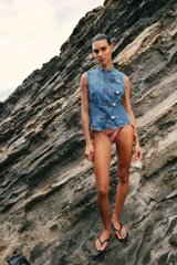 Top de denim sin mangas, con cuello mao y cierre frontal cruzado con trabillas y botones metálicos.