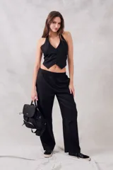 Chaleco negro con escote halter, corte al cuerpo y cierre frontal con botones.