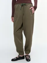 Pantalón tipo jogger de algodón con cintura elástica y cordón ajustable. Presenta un corte relajado, bolsillos laterales y puños elásticos en los tobillos.