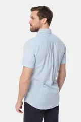Camisa de lino de manga corta con estampado a cuadros en tonos celestes y blancos, cuello con botones y bolsillo ojal en el pecho.