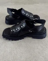 Sandalias negras de cuero vacuno con plataforma y hebilla lateral.