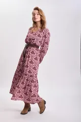 Vestido largo de corte holgado con estampado floral en tonos rosa y marrón. Tiene escote en V, mangas largas abullonadas y cinturón marrón de cuero sintético.