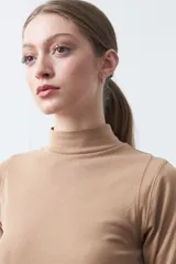 Polera de algodón color blanco, con cuello alto y mangas tres cuartos. Presenta un diseño ajustado al cuerpo con costuras decorativas en las sisas.