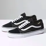 Championes Vans Old Skool color negro con la franja lateral blanca y suela blanca.