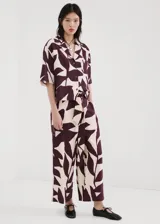 Pantalón largo de corte recto y tiro alto, con estampado abstracto en tonos bordó y crudo. Cuenta con cintura ajustable con elástico y un lazo incorporado para anudar.