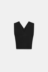 Top de punto negro con escote en pico, tirantes anchos cruzados en la espalda y detalle de drapeado en los hombros con hombreras incorporadas.