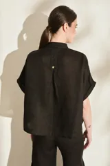 Blusa negra de lino de silueta amplia, con cuello mao y doble hilera de botones dorados en el frente. Cuenta con mangas cortas con vuelta.