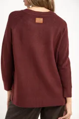 Sweater de punto con textura acanalada, cuello redondo y mangas largas. Presenta un diseño de calce holgado con ruedo redondeado y aberturas laterales.