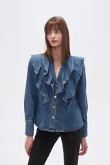 Camisa de jean azul con volados grandes en el frente, escote en V y cierre frontal con botones plateados.