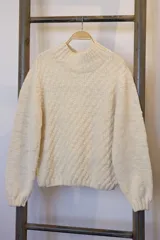 Sweater color crema de lana merino con cuello alto y mangas largas.