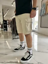 Bermuda cargo de jean color beige, con bolsillos laterales con solapa en las piernas y corte holgado.