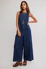 Mameluco enterito de denim azul oscuro, sin mangas, con escote redondo, costuras a contratono y piernas de corte muy ancho y amplio.