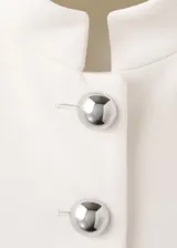 Chaqueta de diseño recto color blanco, con cuello mao, manga larga con puños abotonados, cierre frontal de botones y bolsillos de ribete delanteros.