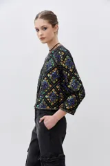 Saco corto negro con estampado geométrico de lentejuelas multicolor, cuello redondo y cierre frontal.