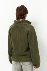 Buzo negro de teddy con cuello alto y cierre de cremallera parcial. Presenta bolsillos de nylon en la parte inferior delantera.