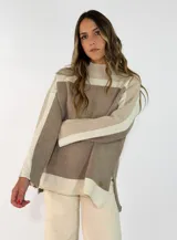 Sweater de punto con diseño de bloques de color en tonos neutros, cuello alto y mangas largas. Presenta un corte holgado con aberturas laterales en el ruedo y un pequeño aplique metálico decorativo.