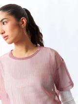Top cropped de manga corta, color rosado, de tejido símil transparente con sutil brillo de fibras metálicas.