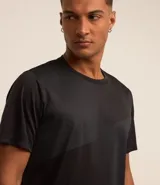 Remera deportiva de hombre, color gris claro, con cuello redondo y manga corta. Presenta un sutil efecto degradado o panel de color más claro en la zona del pecho.