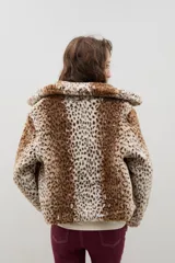 Campera corta de piel sintética en color crema, con cuello amplio tipo solapa y cierre frontal.