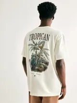 Remera beige de manga corta con estampa frontal con la palabra 'Tropican' en letras negras y detalles en color bordó.