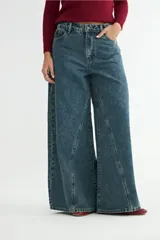 Jean de corte wide leg con diseño de costuras verticales decorativas en el frente, tiro medio y cierre frontal con botón y cremallera.