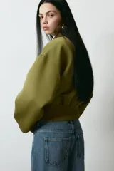 Jean de tiro alto y corte baggy, confeccionado en denim de algodón rígido en tono azul medio con efecto deslavado. Presenta diseño de cinco bolsillos, trabillas para cinto y cierre frontal con botón y cremallera.