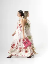 Vestido largo confeccionado en mezcla de tencel y lino, con fondo off white y estampado floral en tonos rosados, rojos y verdes. Cuenta con escote en V pronunciado, breteles anchos ajustables con lazos en los hombros, corte bajo el busto y falda amplia con volados escalonados.
