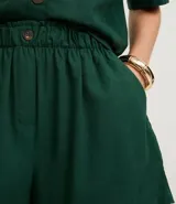 Short runner de viscolino, con cintura elástica, botón decorativo y bolsillos laterales. Presenta un corte evasé holgado con bajo redondeado.