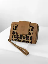Mini billetera Chabas confeccionada en cuero con detalle frontal en pelo con estampado animal print. Cuenta con solapa de cierre con logo de búho grabado y correa de muñeca extraíble.