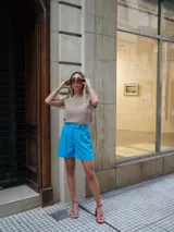 Short de vestir celeste con pinzas delanteras y cierre con botón.