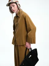 Camisa oversize de lyocell color tostado, con cuello clásico, cierre frontal de botones y mangas largas con puños anchos. Presenta un diseño de corte relajado con caída fluida.