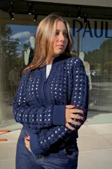 Chaqueta de punto calado color azul marino, con cierre frontal completo, cuello alto y puños tejidos en punto elástico.