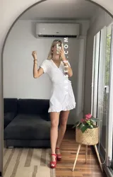 Vestido corto rojo con escote cruzado, mangas cortas y falda con volados. Se ajusta con lazo lateral tipo pareo.